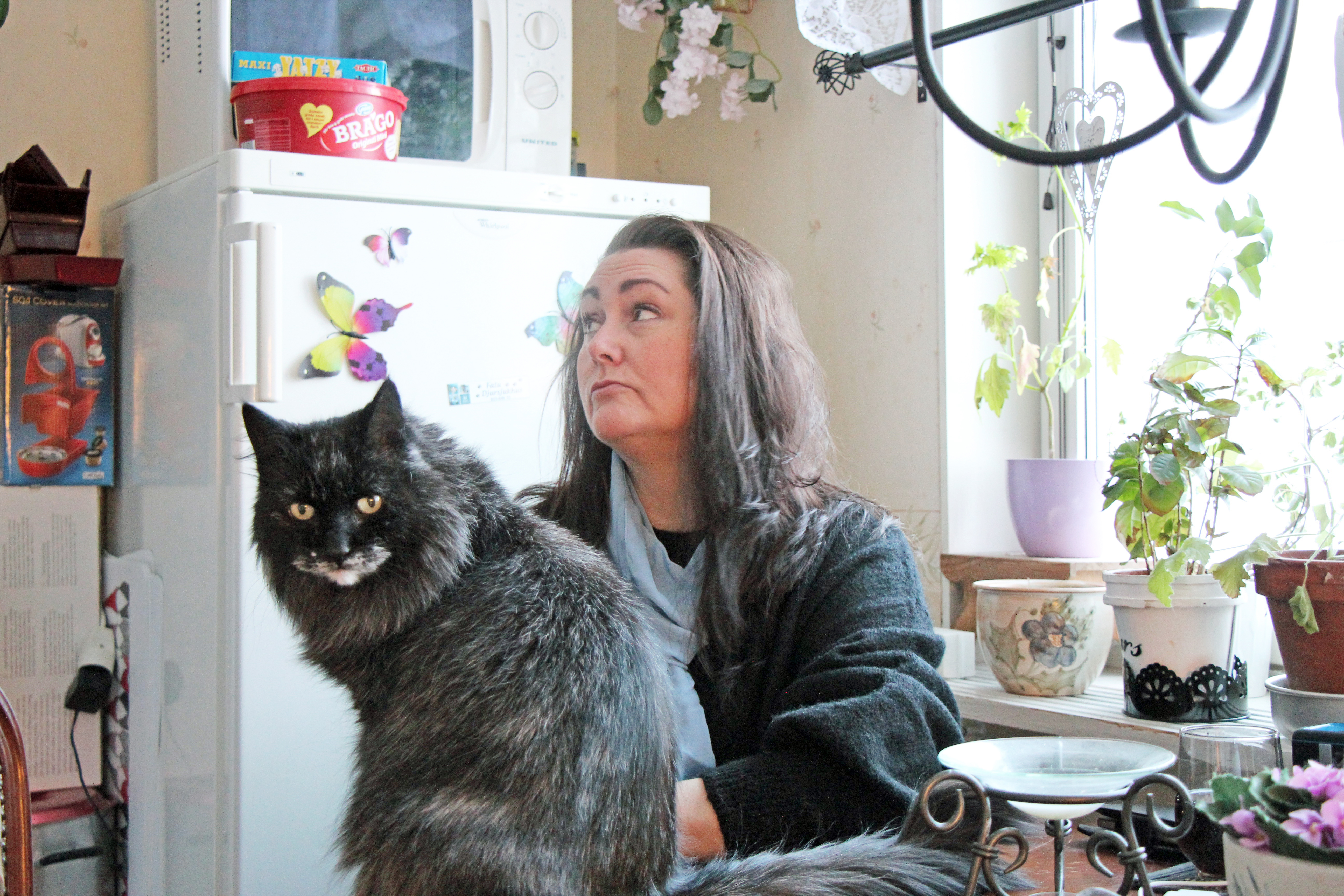 Petra Karlsson sitter vid sitt köksbord. På bordet sitter en katt.