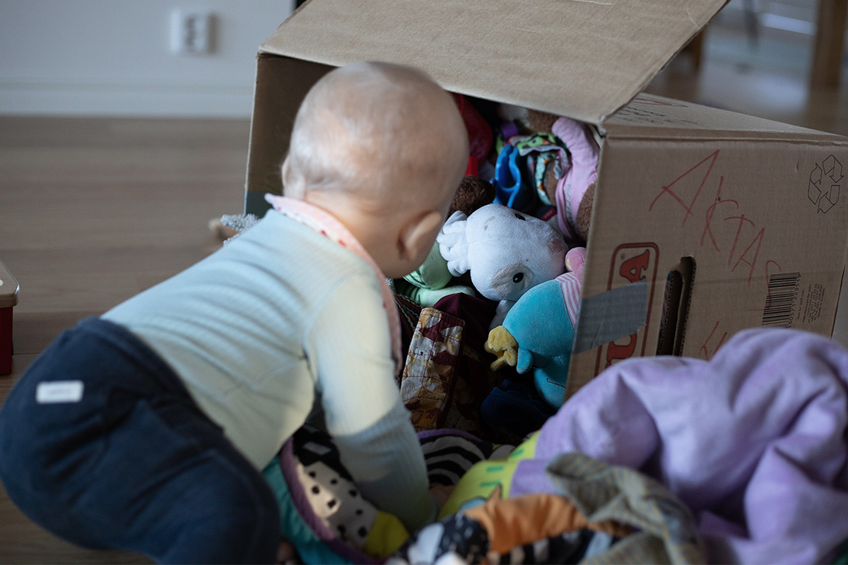 Ett litet barn packar upp sina leksaker ur en flyttlåda.