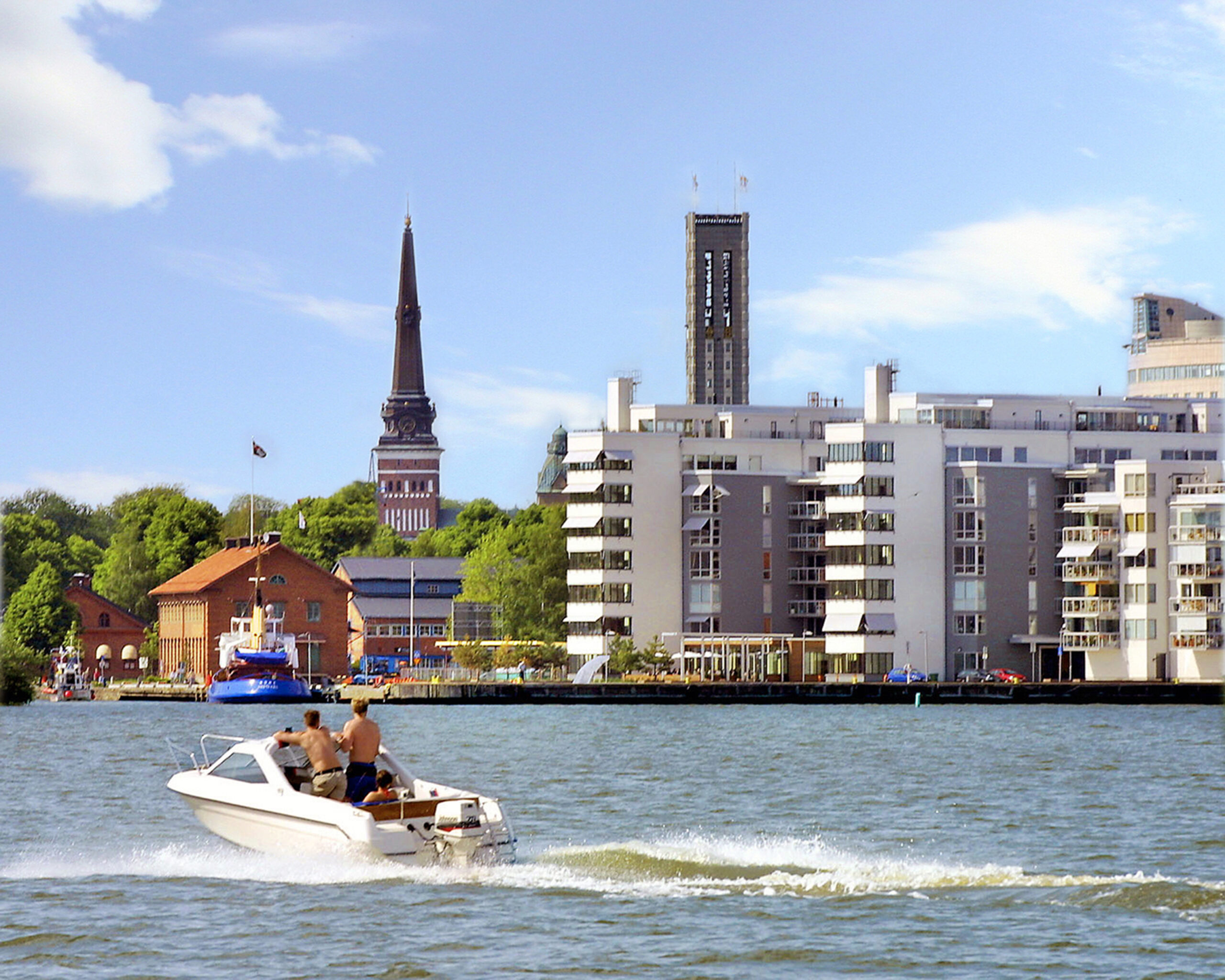 Västerås sett från vattnet. En båt med två män och en kyrka i bakgrunden.