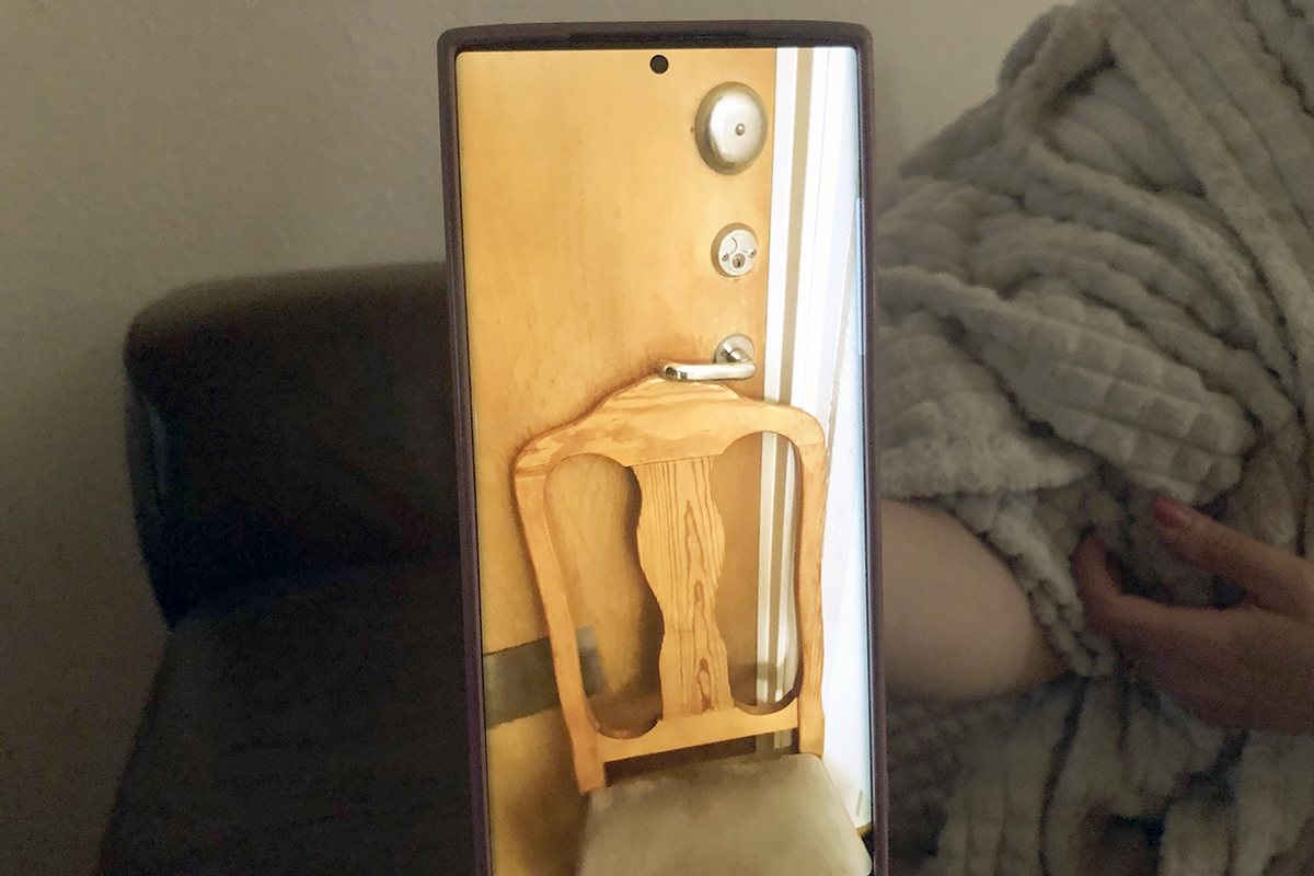 En mobilskärm visar en bild på en stol under ett dörrhandtag.