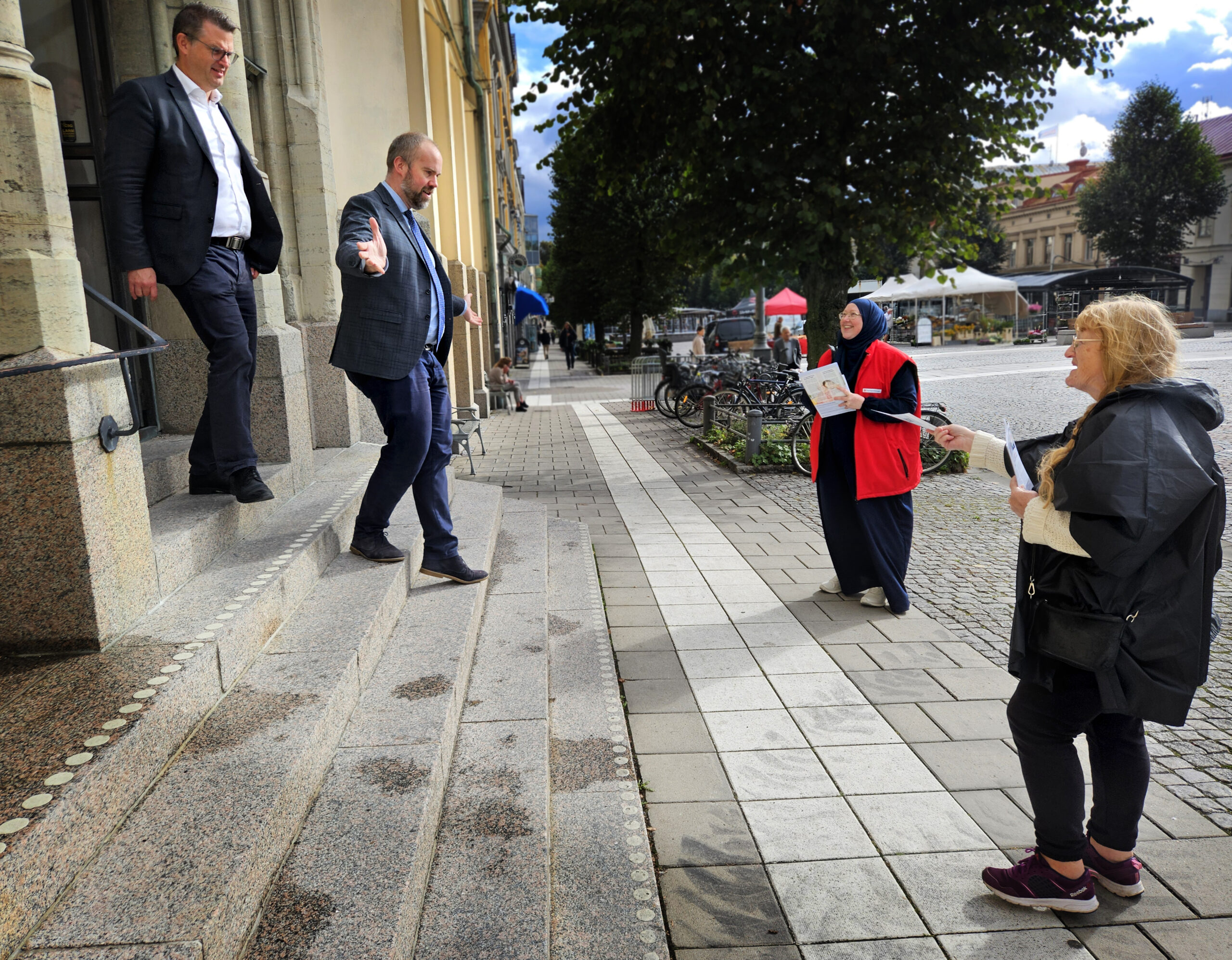 Politiker kommer ner från rådhusets trappa samtidigt som Hyresgästföreningen protesterar mot försäljningen av Öbolägenheter.