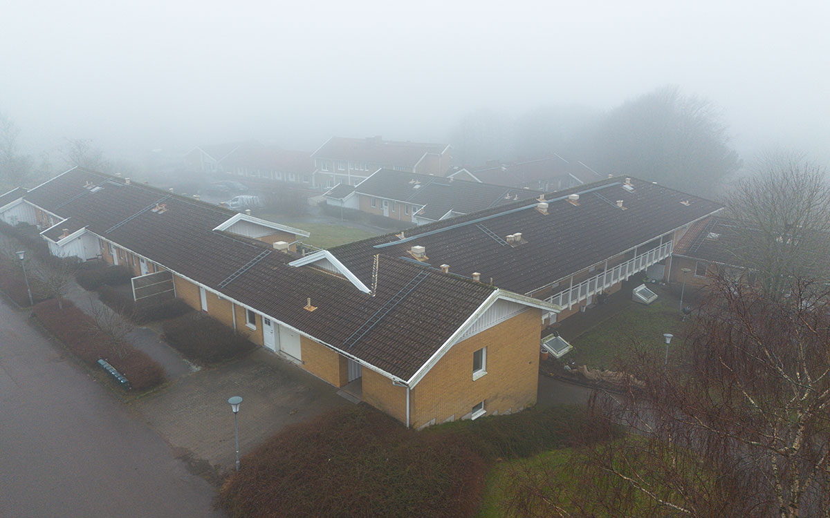 En bild tagen ovanifrån som visar flera ihopbyggda bostadshus i gult tegel en dimmig dag.