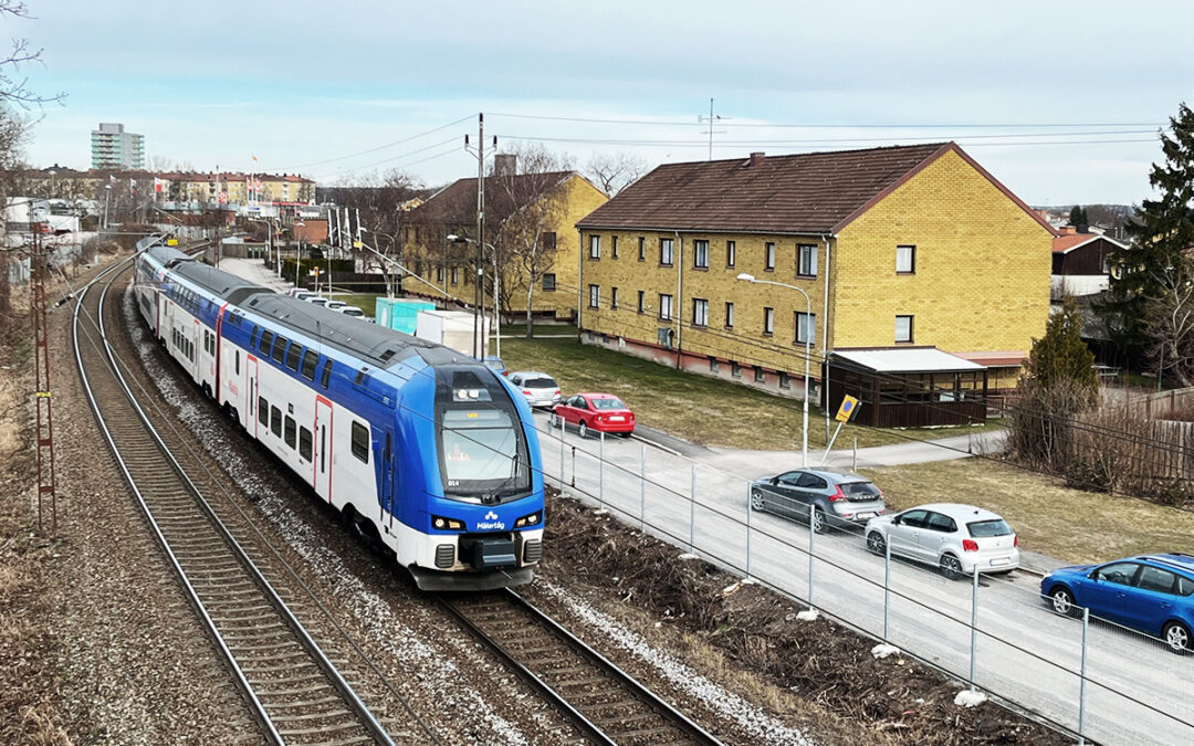 Regionaltåg passerar hyreshus i Norrköping.