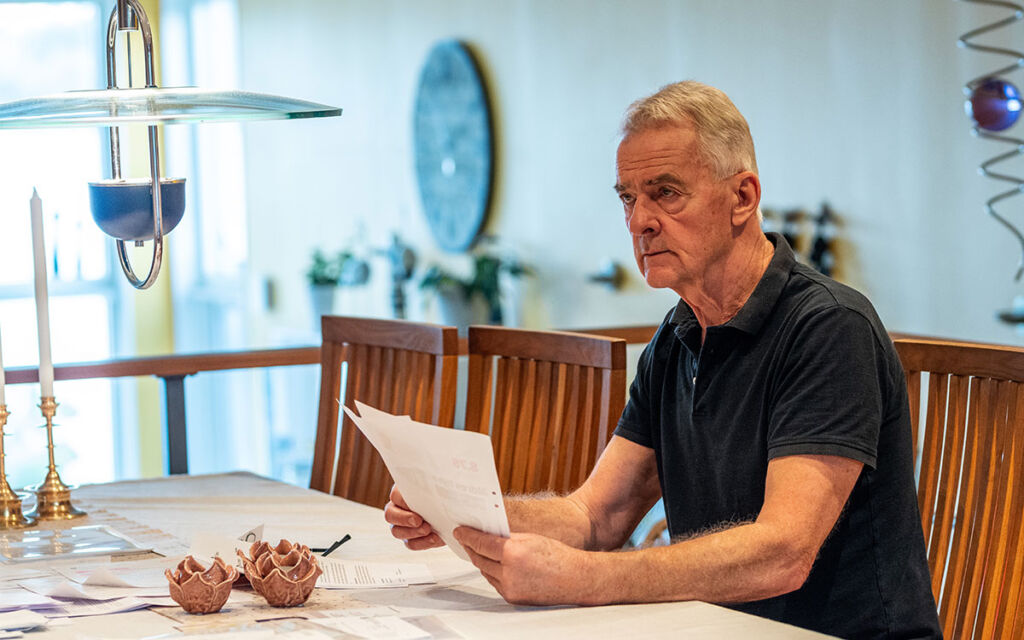 Thomas Nordqvist sitter vid köksbordet med många dokument.